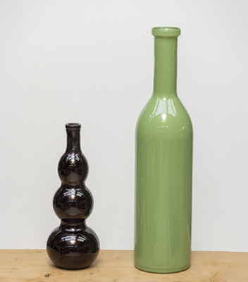 Vasi decorativi in vetro, uno di colore nero e dalla forma sinuosa l'altro di colore verde e dall'aspetto classico. Perfetto per arredamenti dallo stile chic e moderno.