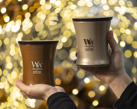 Vivai-Tomasi-candele_WW Candele WoodWick in 2 profumazioni e colori. La candela marrone ha profanazione: volcanic orris; la candela dorata ha produzione: sparkling pomelo.